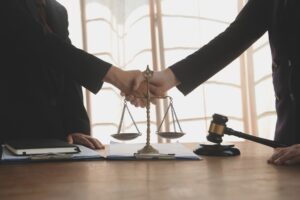 Lawyer shaking hands with a client making about documents, contracts, agreements, cooperation agreements with a female client at the lawyer's desk and a hammer at the table.