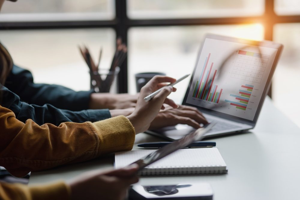 Coworkers review data on a laptop. What are the 5 P’s of a business plan?
